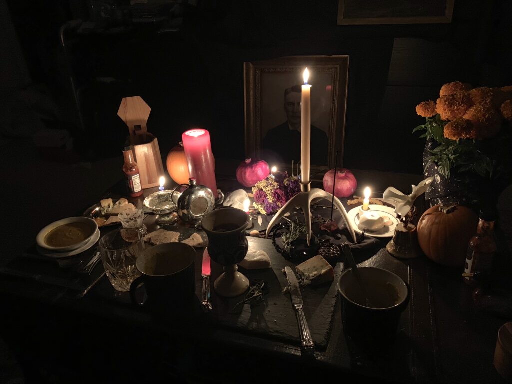 Samhain Altar with candles, goddess statue, ancestor photos, and a marigold plant